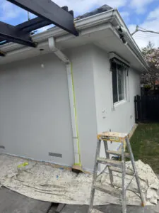 Rear wall rendered around the pergola, with subfloor vents and a masked downpipe.
